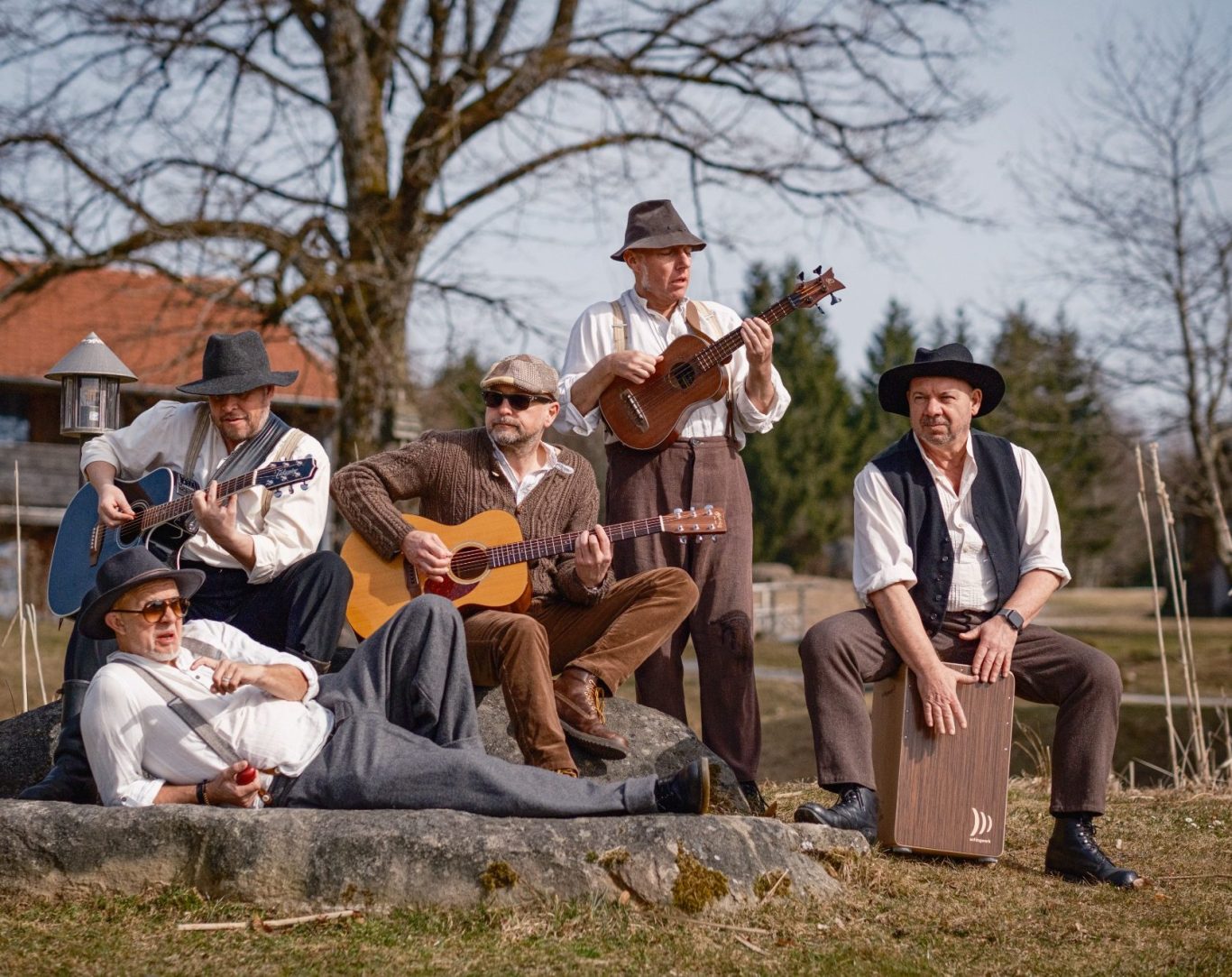 Woidbluad Probe im Freien Fünf Woidbluad Musiker in traditioneller Kleidung spielen verschiedene Instrumente im Freien.