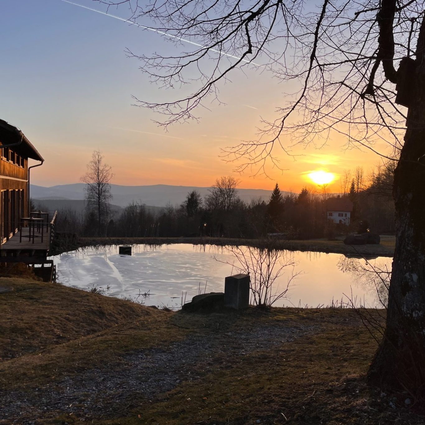 Sonnenuntergang auf der GutsAlm Harlachberg Sonnenuntergang auf der GutsAlm Harlachberg an einem ruhigen Teich mit umliegender Landschaft und Bäumen.